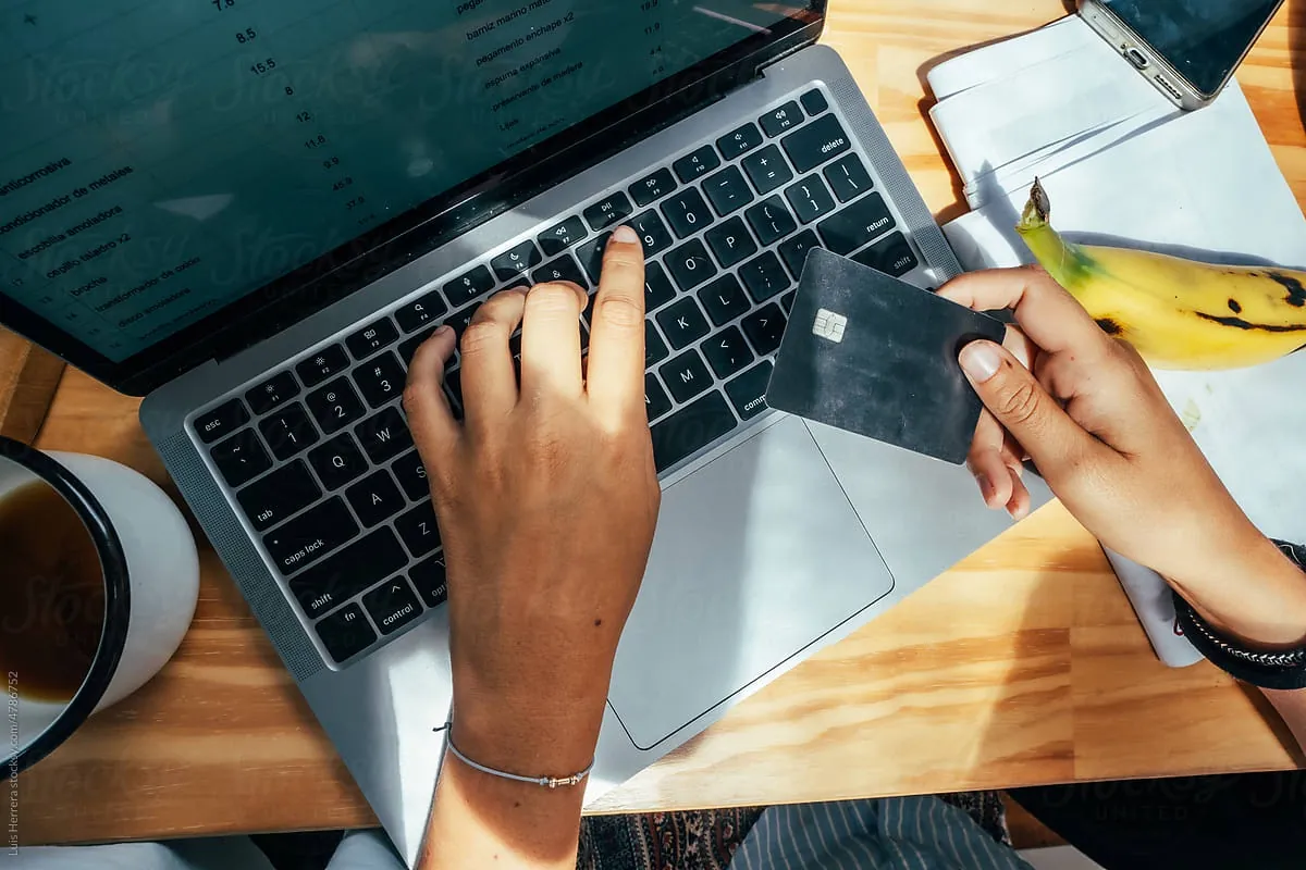 Hands holding a credit card while typing on a laptop