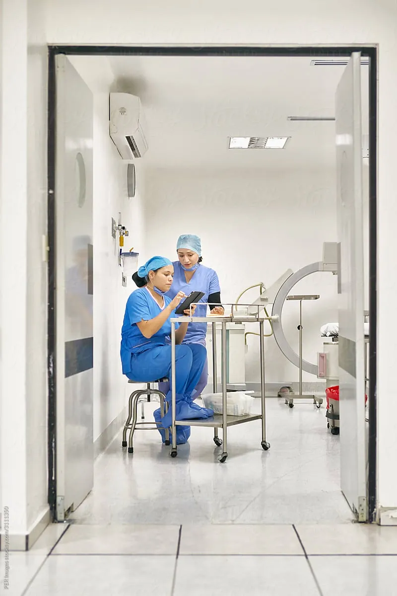 Two medical workers reviewing a tablet in a hospital imaging room